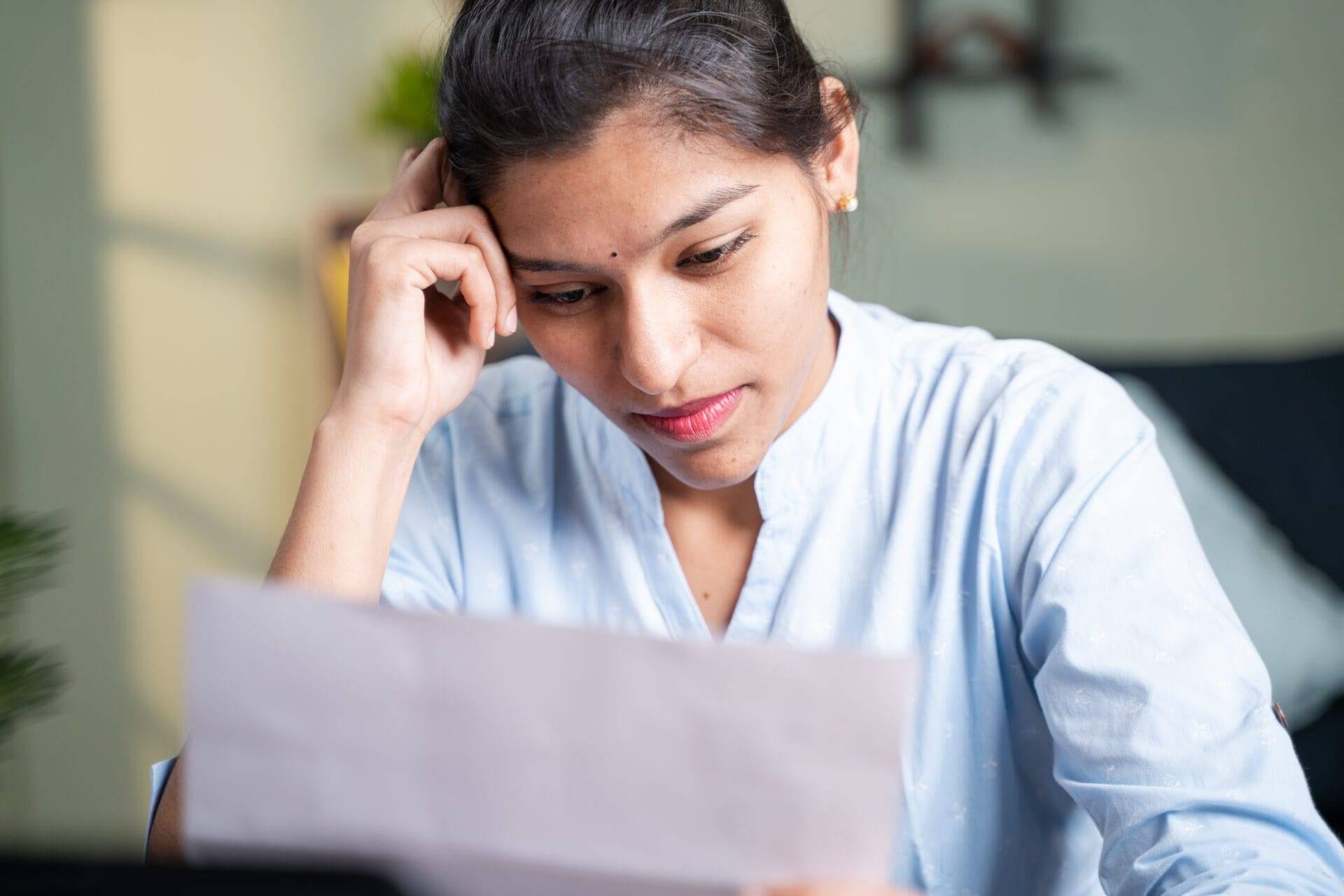 Business lady in office experiencing work stress, looking concerned at paperwork.