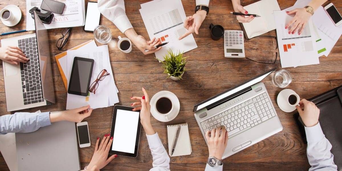 Business Services Workplace Wellbeing2 Landscape birdseye view image of people sat around a table at a business meeting - representing the Purple House Clinic's Workplace Wellbeing Service.